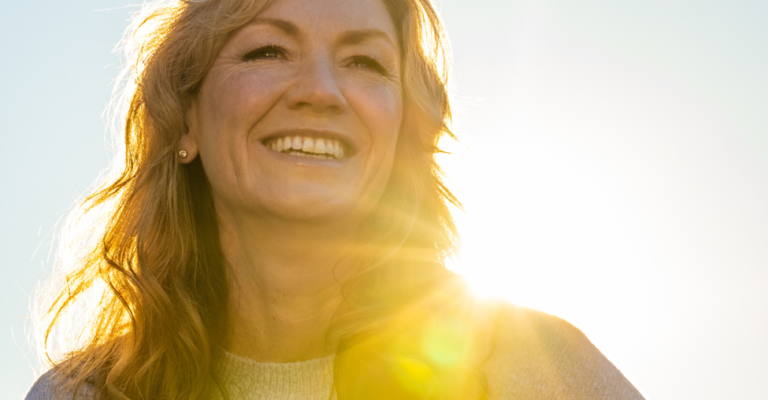 smiling women smiling with the sun shining behind her